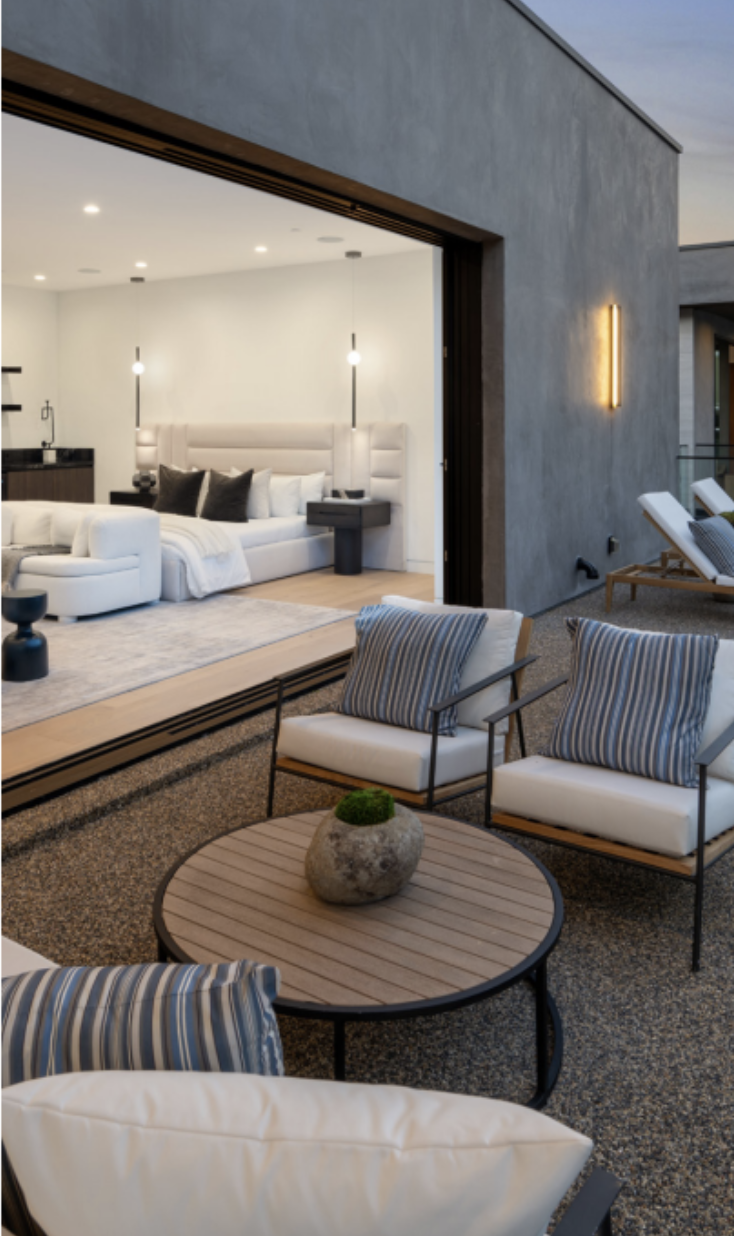 Bright modern living room with floor-to-ceiling windows, indoor pool, cozy fireplace, and lush greenery creating a seamless indoor-outdoor feel.